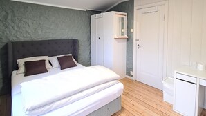 A bedroom with a bed, wardrobe, and desk.