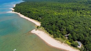An aerial view of a coastal area with a beach and dense forest.