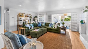 A spacious living room with a large sectional sofa, a round coffee table, and a bookshelf.