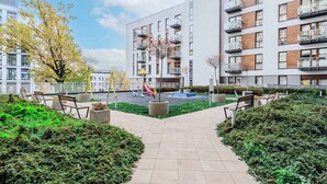 A modern apartment building with balconies, a playground, and a paved walkway. - Lumina apart with parking in Center (Łódź)