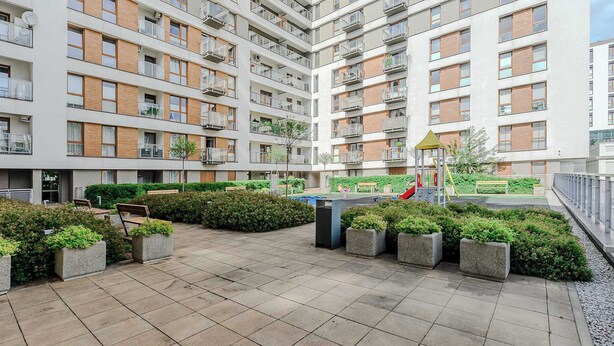 A multi-story residential building with balconies, a playground, and landscaped areas.