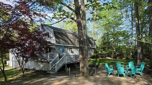 A house with a deck, outdoor seating, and a fenced yard. - Spacious 6-bedroom home just steps from outdoor adventures! (Laconia)