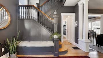 A staircase with dark wood railings and a white balustrade, leading to a landing with a bench and potted plants.