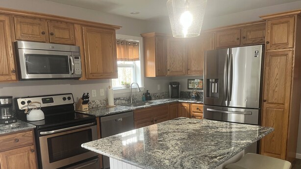 Una cocina moderna con armarios de madera, electrodomésticos de acero inoxidable, encimeras de granito y una isla central con asientos.