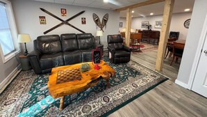 Una sala de estar con un sofá de cuero, una mesa de centro de madera y una alfombra estampada.