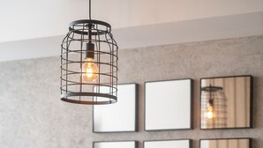 Un comedor con una mesa redonda dispuesta para cuatro personas, rodeada de sillas. Hay una lámpara colgante sobre la mesa.