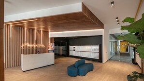 Una zona de recepción moderna con un revestimiento de madera en listones, una mesa de recepción y un área de estar.