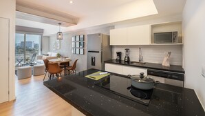 Una cocina moderna con cubierta negra, electrodomésticos de acero inoxidable y un área de comedor con mesa y sillas.