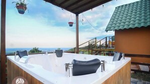 A spa area with a wooden tub, a wooden deck, and a view of the sea.