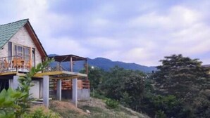 A house with a sloped roof, a balcony, and a view of mountains in the background.