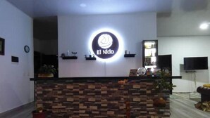 A reception desk with a sign that reads "El Niño," a television mounted on the wall, and a potted plant on the counter.