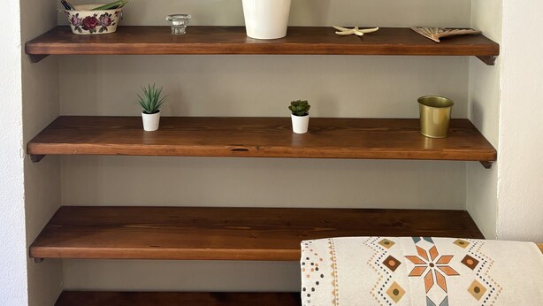 A set of wooden shelves with books, potted plants, and decorative items.