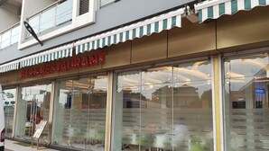 A bar and restaurant with a striped awning and large glass windows. - Hotel Indigo (Kinshasa)