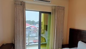 A hotel room with a bed, a desk, and a view of buildings and a staircase outside. - Hotel Indigo (Kinshasa)