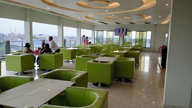 A spacious indoor area with green seating and a large window offering a view of the cityscape. - Hotel Indigo (Kinshasa)