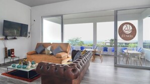 A modern living room with a leather sofa, a flat-screen TV, and a dining area with a table and chairs. - Romantic Cabin with Jacuzzi Azulejo (Acacías)