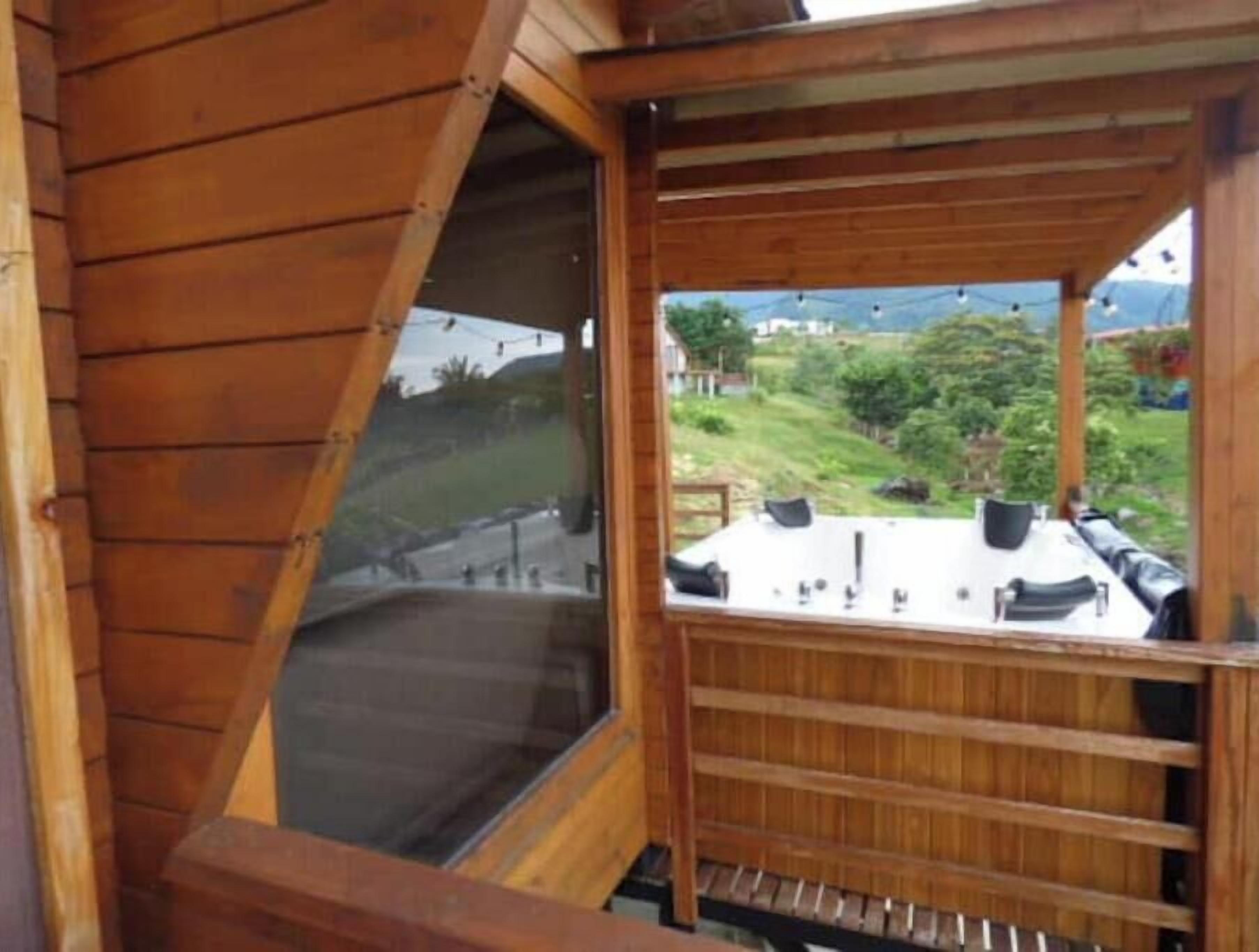 Een houten interieur met een raam dat uitkijkt over een begrazend landschap en een witte tafel met stoelen.