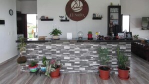 A reception area with a stone mosaic counter, potted plants, and a wall-mounted logo. - Romantic Cabin with Jacuzzi Azulejo (Acacías)
