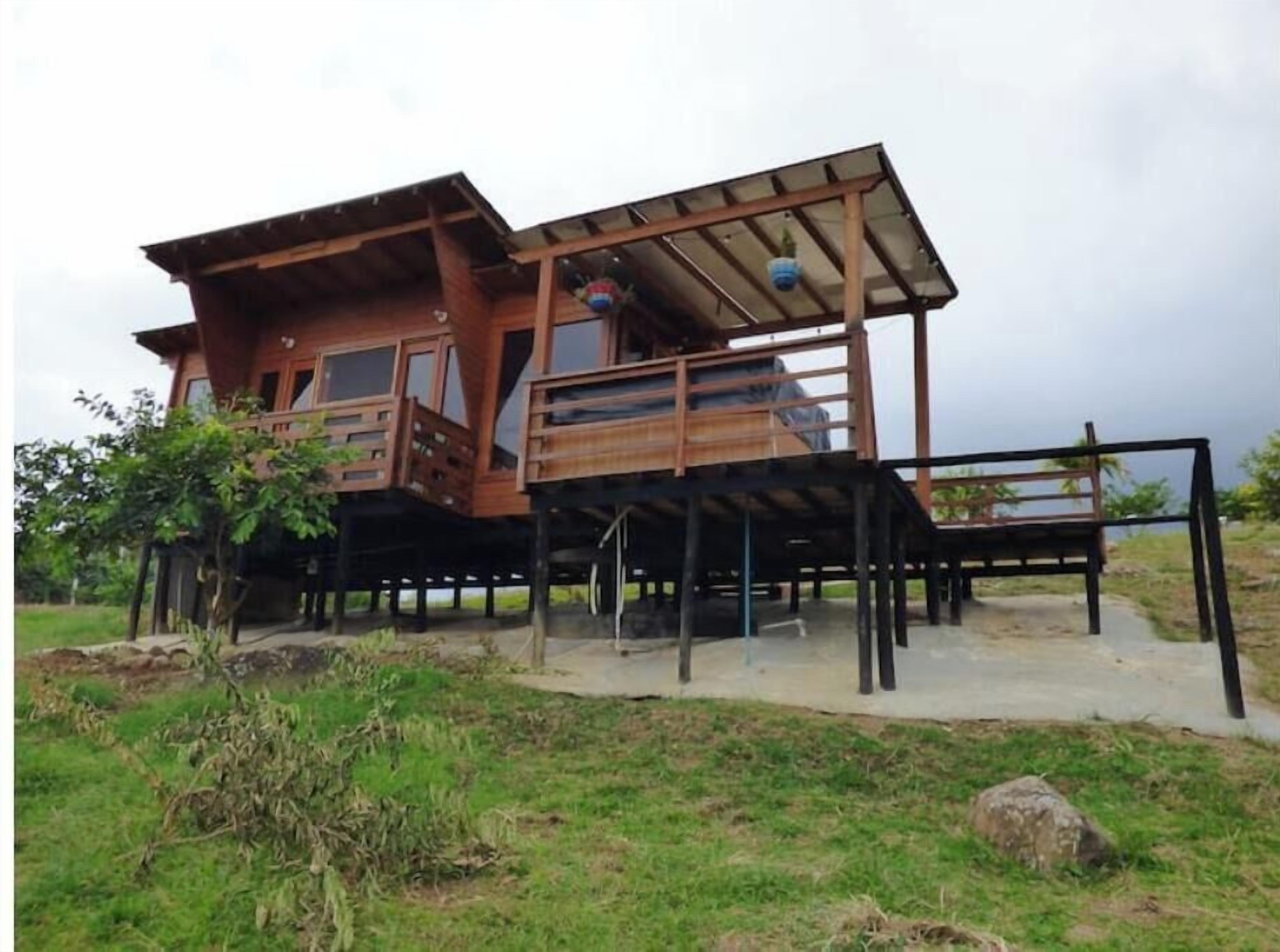 Een houten huis met meerdere verdiepingen en een balkon, gelegen op een gazon met uitzicht op de lucht.