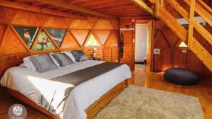Un dormitorio acogedor con una cama grande, paredes de madera y techo inclinado.