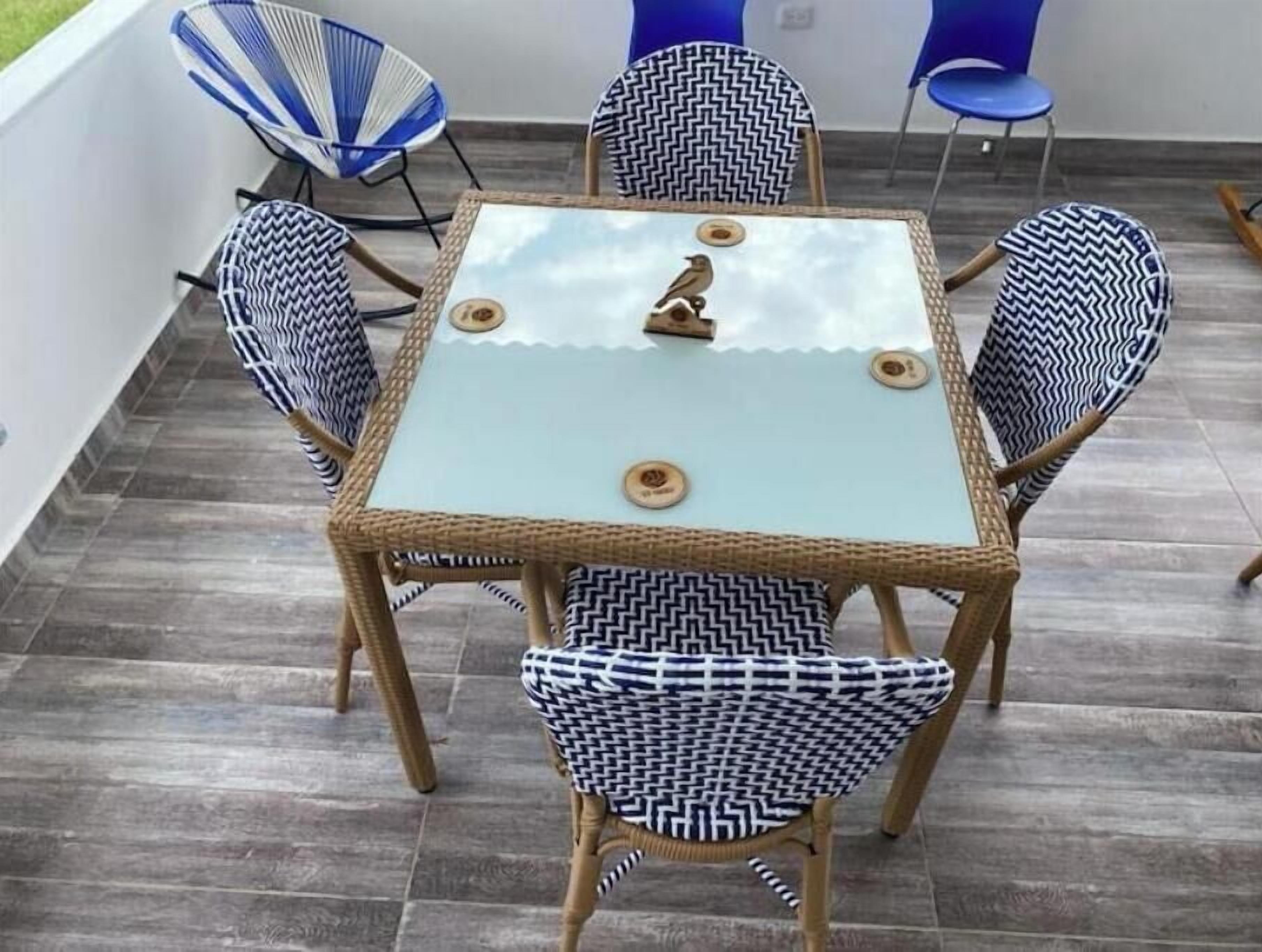 A square table with a glass top and four chairs with patterned cushions.