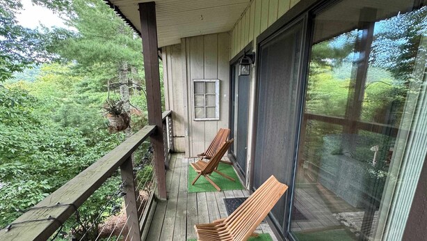 Une terrasse en bois avec deux chaises en bois, une fenêtre et une porte.