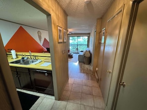 A narrow hallway leading to a kitchen with a sink and a dining area with a table and chairs. - HBVD215  Boho Beech Bunny Walking Distance to Resort & Pet Friendly (Beech Mountain)