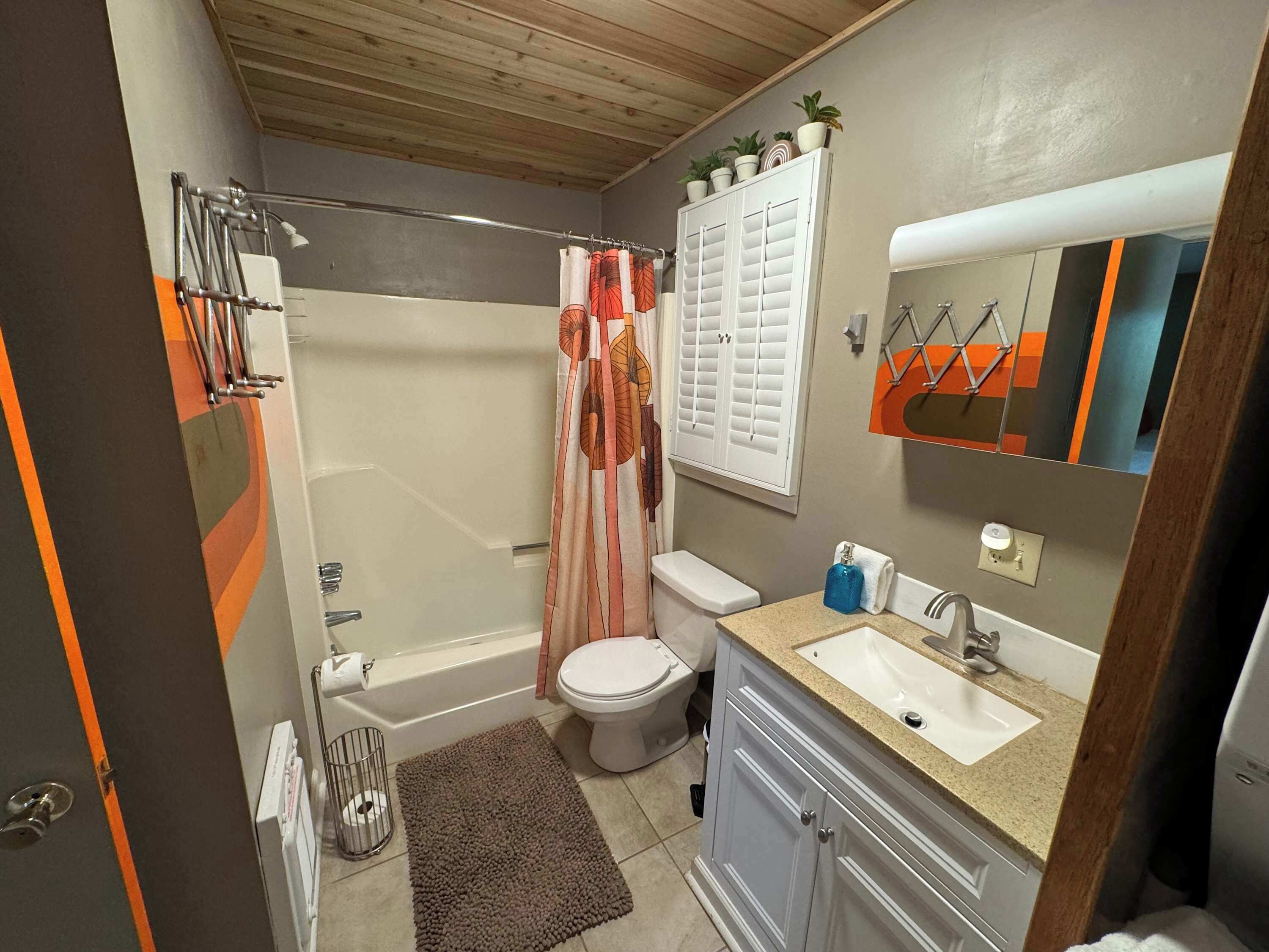 A compact bathroom with a shower, toilet, sink, and mirror.
