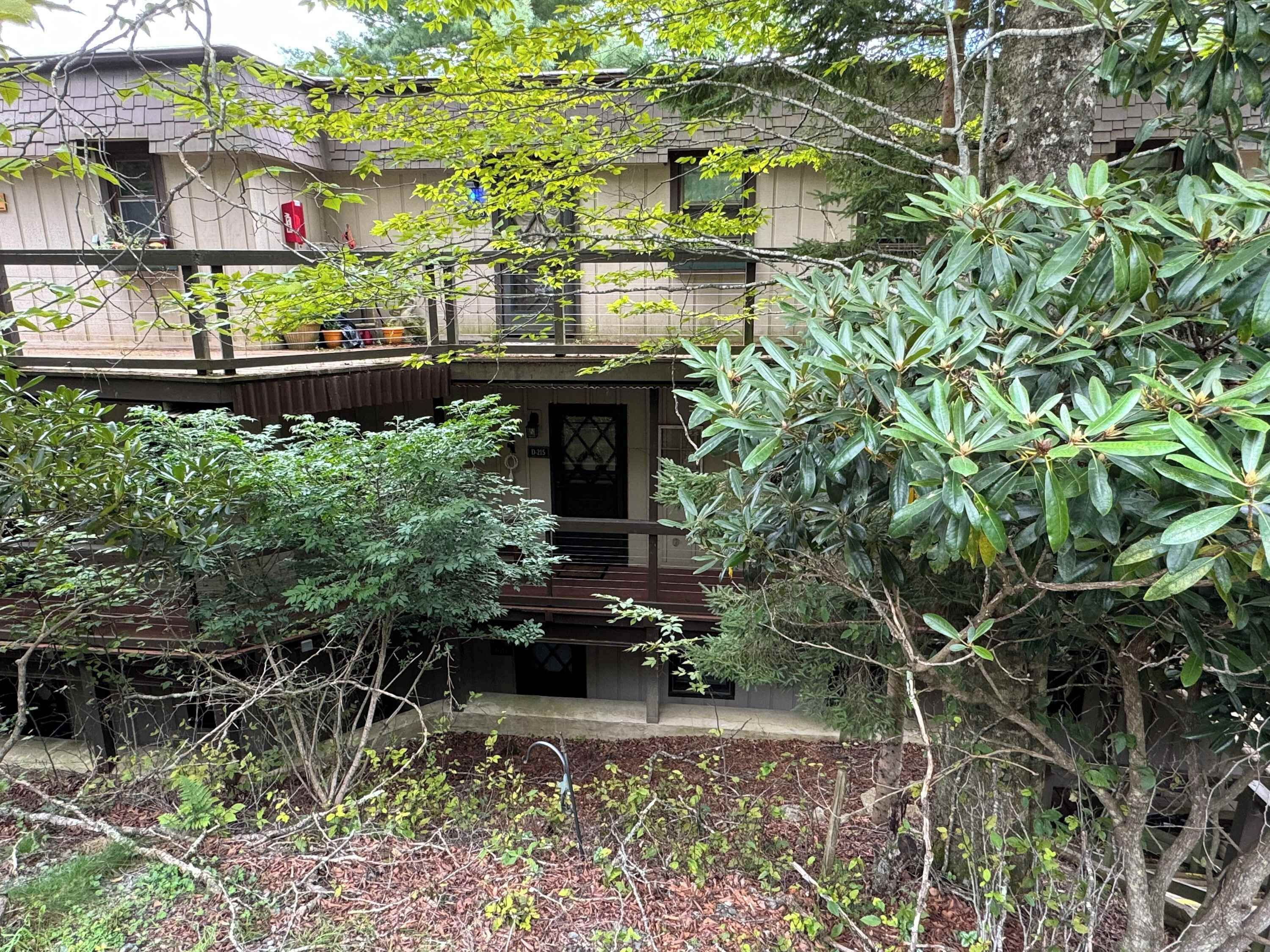 A two-story building with a balcony, surrounded by dense foliage.