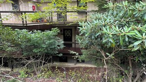 Un bâtiment à deux étages doté d’un balcon, entouré d’une végétation luxuriante.