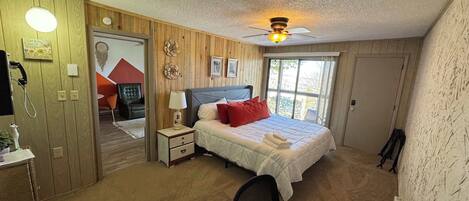 A bedroom with a bed, bedside table, lamp, and a ceiling fan.