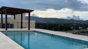 Una piscina con un pergolato e vista sulle montagne.