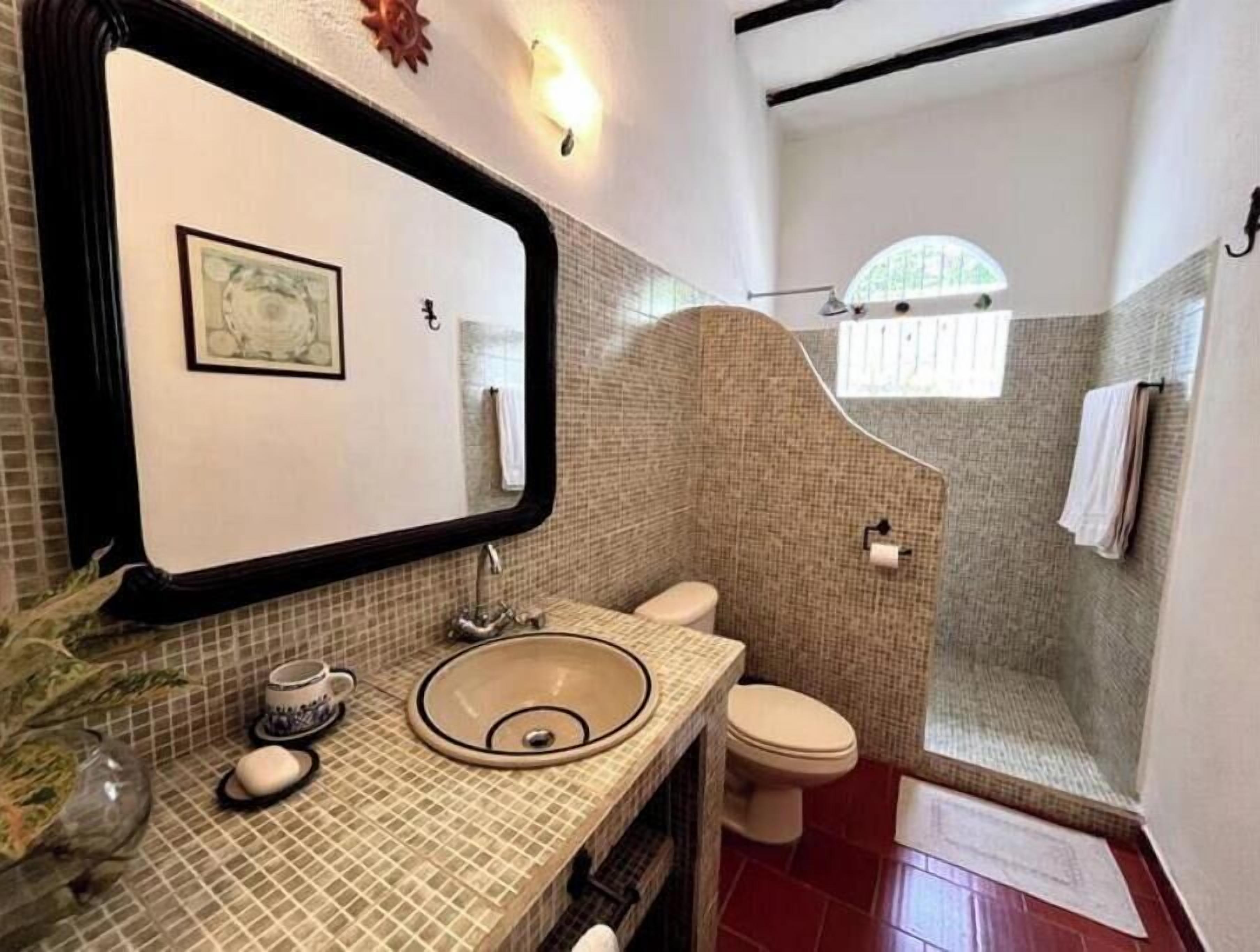 A bathroom with a tiled sink, a toilet, and a shower area.