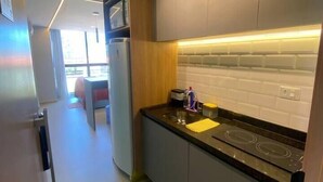 A modern kitchen with grey cabinets, a black countertop, and a white tiled backsplash. - Estudio 311 reserva do cupe byLP (Ipojuca)