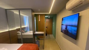 A hotel room with a bed, a TV mounted on the wall, and a window. - Estudio 311 reserva do cupe byLP (Ipojuca)
