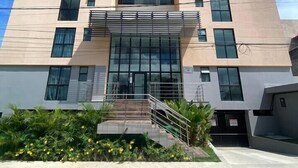 A modern building with a flat facade, large windows, and a central entrance with a staircase. - Estudio 311 reserva do cupe byLP (Ipojuca)