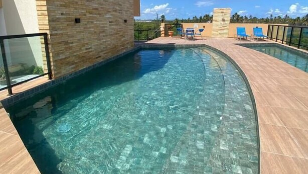 A modern pool area with clear water, a tiled deck, and a wooden wall. - Estudio 311 reserva do cupe byLP (Ipojuca)