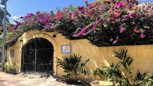 A building with a yellow facade, a black gate, and a sign that reads "Auspicious." - Beautiful room in Choroni (Puerto Colombia 2110)