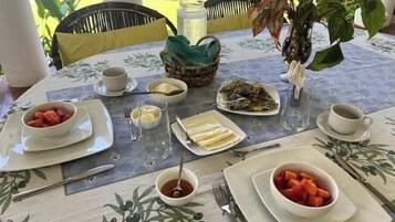 Et bord dækket til morgenmad med tallerkener med mad, kopper og en vase med blomster.