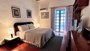 A bedroom with a bed, bedside table, lamp, and a view of the outdoors through a window. - Room for a couple in Choroni (Puerto Colombia 2110)