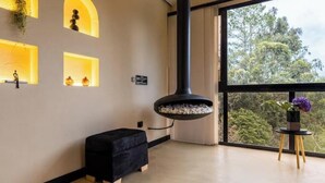 A modern room with a large window, a black hanging light fixture, and a small black ottoman.