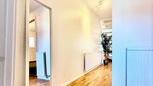 A hallway with wooden flooring, white walls, and a radiator. - Brilliant family getaway in Stockholm - 4 Guests (Kista)