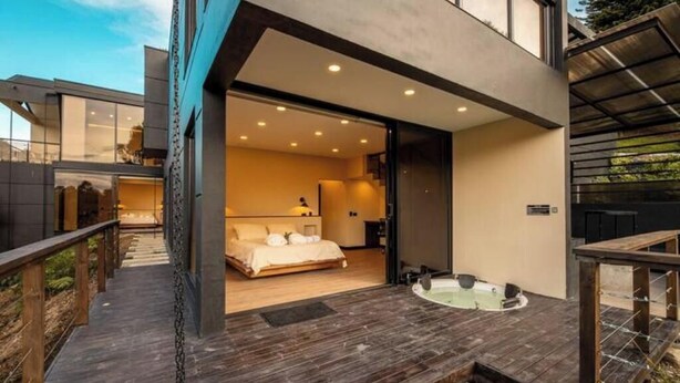 Une chambre moderne dotée d’un grand lit, d’une salle de bain privative et d’un jacuzzi sur une terrasse en bois.