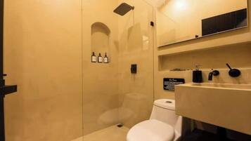 Une salle de bain moderne avec une douche à parois de verre, des toilettes blanches et un lavabo doté d’un robinet noir.