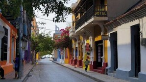 A street with colorful buildings, including a hotel with balconies and flower boxes. - Room for 2 people in Playa Salguero (Gaira)