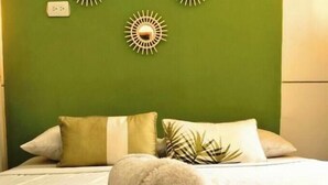 A neatly made bed with a rolled towel in the center, two pillows, and a decorative wall piece. - Room for 2 people in Playa Salguero (Gaira)