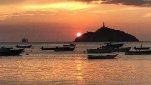 A sunset over a body of water with several boats and a distant island. - Room for 2 people in Playa Salguero (Gaira)