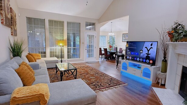 A spacious living room with a grey sofa, a coffee table, and a flat-screen TV. - Cozy Corner Near I-20 & 360, Heart of DFW, Quiet Cul-de-Sac Stay (Arlington)