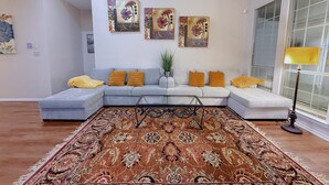 A modern living room with a sectional sofa, a patterned rug, and wall art. - Cozy Corner Near I-20 & 360, Heart of DFW, Quiet Cul-de-Sac Stay (Arlington)