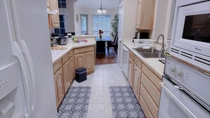 A modern kitchen with white appliances, wooden cabinets, and a central island. - Cozy Corner Near I-20 & 360, Heart of DFW, Quiet Cul-de-Sac Stay (Arlington)